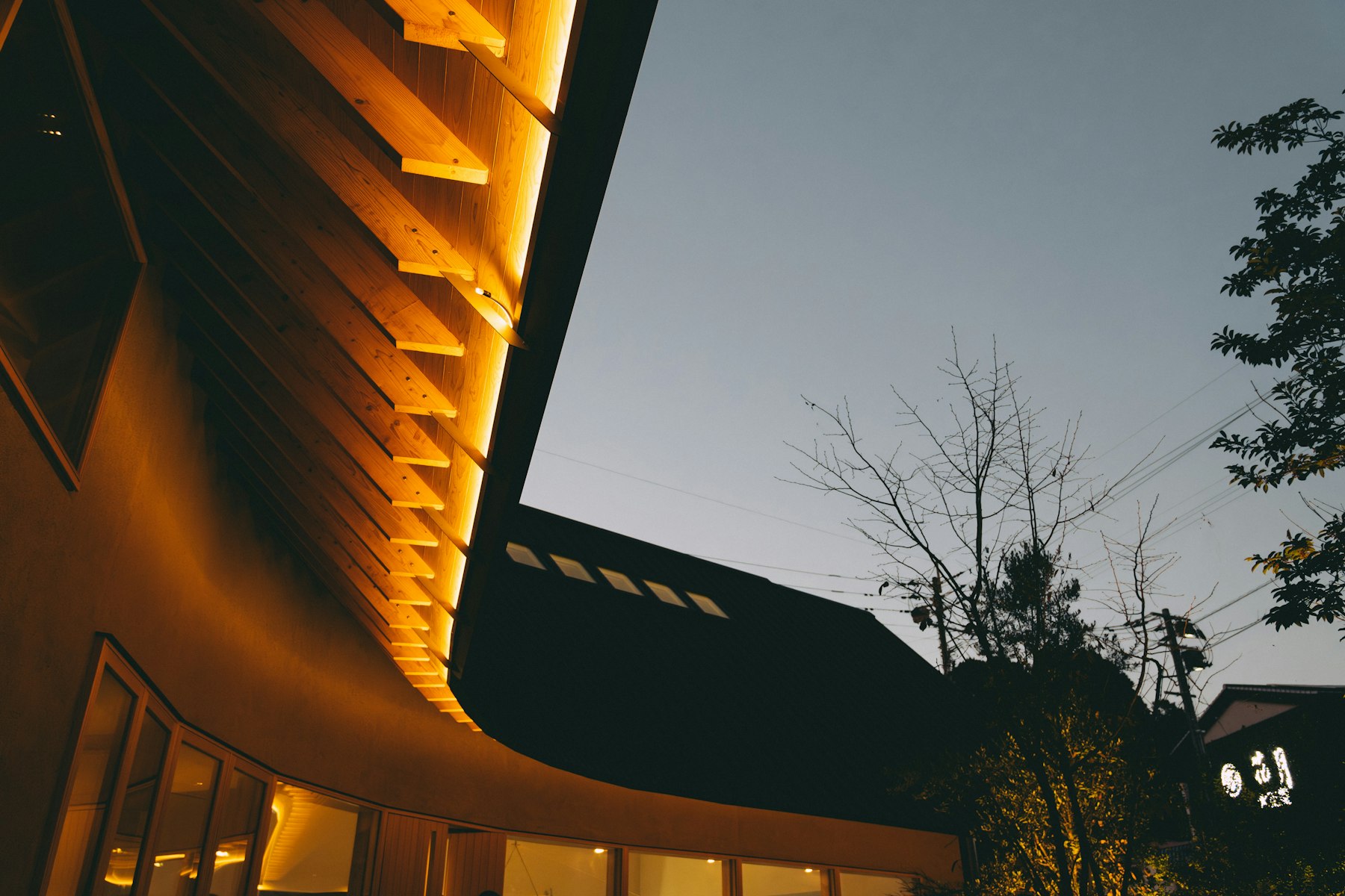 Warm verlichte houten luifel van een modern gebouw in de schemer